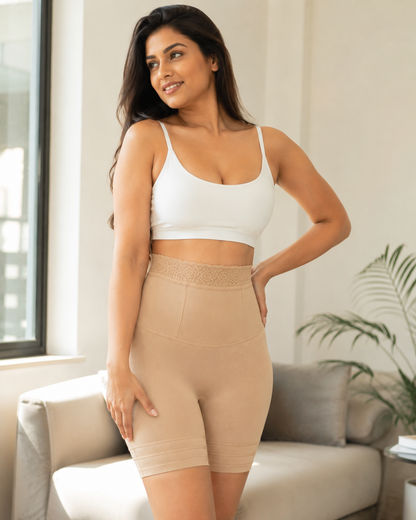 Woman wearing a white sports bra and beige shapewear in a living room setting